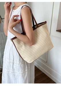 Detail of yellow striped canvas tote bag with reinforced brown leather handles and stitching