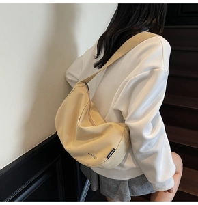 Rückansicht eines Models mit einer großen beige Segeltuch Hobo Tasche in Halbmondform