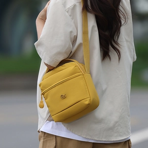 Détail de la sacoche jaune en nylon avec logo métallique et poche zippée