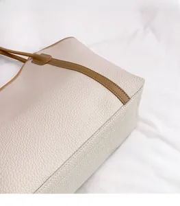 Detail of off-white lychee grain leather tote with brown straps and contrast stitching