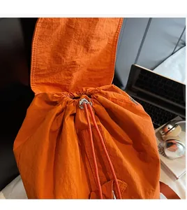 Détail du sac à dos orange en nylon avec cordon de serrage et rabat imperméable
