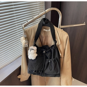 Close-up of black nylon drawstring crossbody bag with multi-pockets and plush bear charm