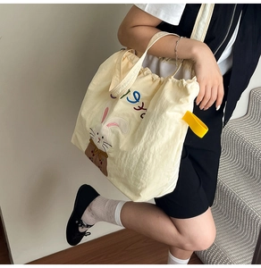 Detail of canvas tote bag featuring cute rabbit embroidery and contrasting yellow handles