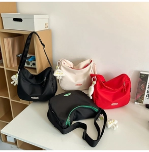Detail view of large nylon dumpling bags in multiple colors with cute doll pendants