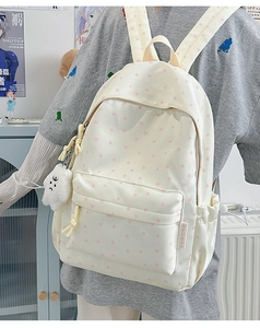 Detail of white canvas backpack with pink star pattern and plush cloud pendant charm