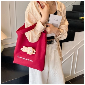Detail of burgundy canvas tote bag featuring a 3D plush bear and white embroidery