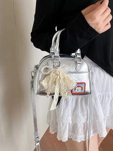 Sac bowling argenté avec nœud en dentelle et chaîne de perles porté par un mannequin