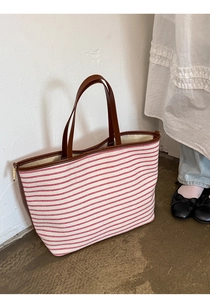 Detail of red striped canvas tote with brown leather handles and fine stitching accents