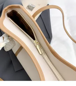 Detail view of gold zipper and brown striped lining on cream textured leather tote bag