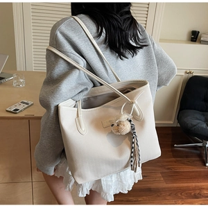 Detail of herringbone texture tote bag with plush bear charm and check tassel