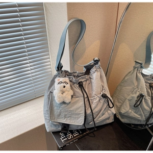 Detail of light blue textured nylon crossbody bag with drawstring and plush dog charm