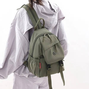 Olive green nylon backpack showing front zip pocket and side elastic compartments