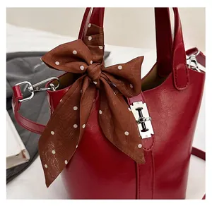 Dettaglio borsa a secchiello in pelle rossa con chiusura argento e fiocco in seta a pois