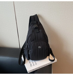 Detail of black pleated nylon crossbody bag with silver logo and adjustable wide strap