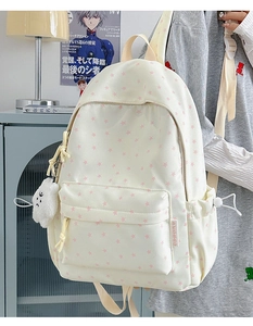 Side view of white star print backpack with cloud pendant and adjustable drawstring pocket