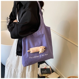 Detail of purple canvas tote bag with 3D cat doll decoration and wide shoulder strap