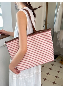 Detail of red and white striped canvas tote bag with brown leather handle and side buckle