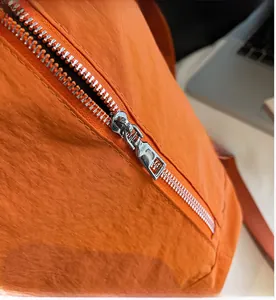 Gros plan sur la fermeture éclair en métal et le nylon ripstop orange du sac à dos