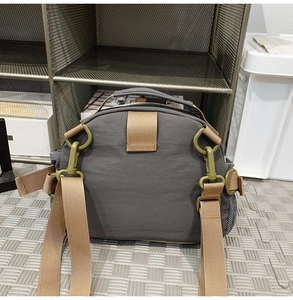 Detailed view of dark grey nylon crossbody bag with brown straps and side mesh pockets