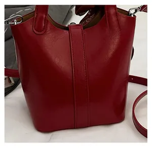 Dettaglio della borsa a secchiello rossa con pelle lucida e ganci in metallo argento