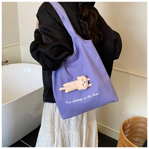 Detail of light purple canvas tote bag with a cute 3D plush cat doll on simple indoor background