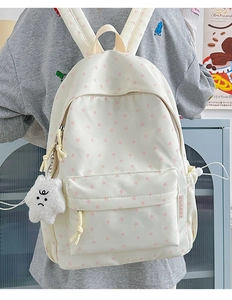 Detailed back view of a cream backpack with pink stars and a plush star charm