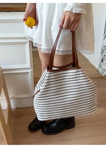Detail view of large canvas tote bag with black and white stripes and brown leather straps