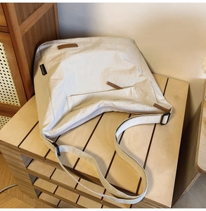 Detailed view of white nylon messenger bag with adjustable strap on wooden bench