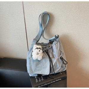 Detail of light blue nylon crossbody bag with drawstring pocket and plush puppy charm