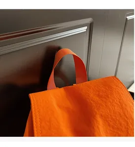 Détail de la poignée de sac à dos orange vif avec coutures renforcées et texture en nylon