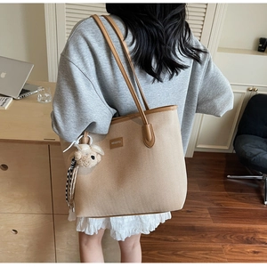 Detail of herringbone tote bag with brown straps and cute white plush bear charm