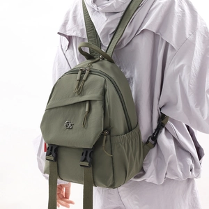 Detail of water-resistant olive green nylon backpack with metal logo and zipper compartments