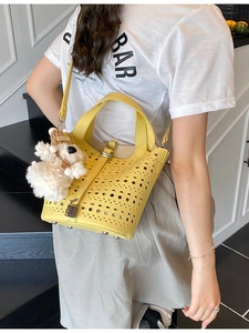 Sac seau jaune ajouré avec découpes géométriques et charme de chien sur un mannequin