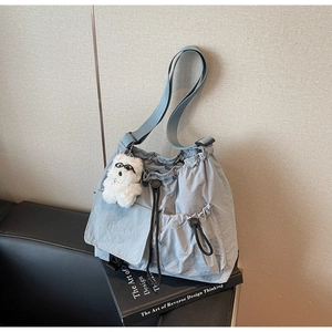 Detail of light blue nylon drawstring bucket bag with a cute plush puppy pendant charm