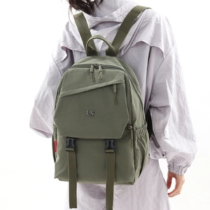 Close-up of olive green nylon backpack featuring front buckle pocket and side logo detail
