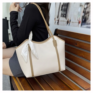 Chic cream tote bag with brown straps and plaid silk scarf on a wooden bench