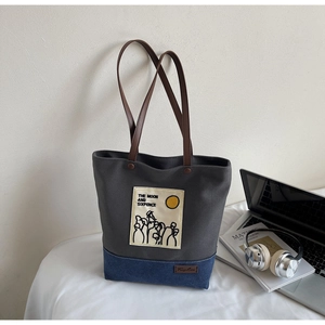 Close-up of canvas tote bag with contrast stitching and brown leather handles
