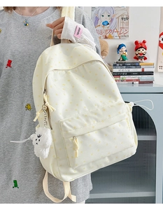 Detail of cream backpack with yellow stars and white cloud plush charm in a casual setting