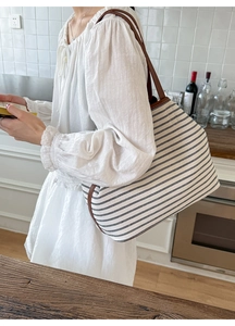 Detail of striped canvas tote bag with brown leather straps shown in kitchen setting