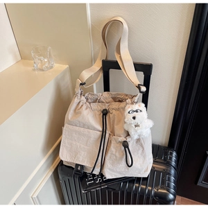 Detail of beige nylon drawstring bucket bag with pockets and cute plush dog charm