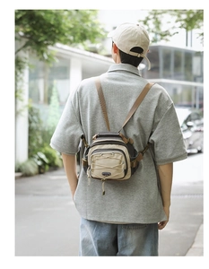 Outdoor view of a beige and grey functional crossbody hiking bag with woven strap