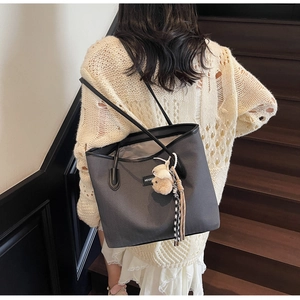Detail of grey tote bag with V-shaped texture, MEIGEE logo and cute bear charm