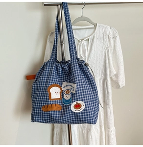 Detail of blue plaid canvas tote with cute food embroidery and drawstring closure