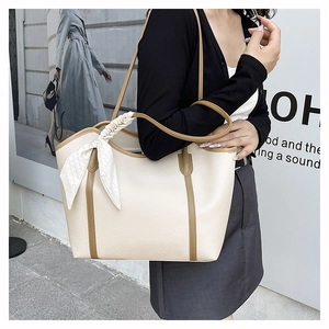 Close-up of beige tote bag with brown handles and floral silk scarf detail in use