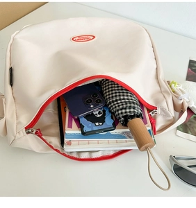 Detail of off-white nylon bag interior showing large capacity for books and umbrella