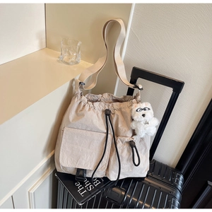Detail of beige nylon crossbody bag with drawstring pockets and plush dog charm