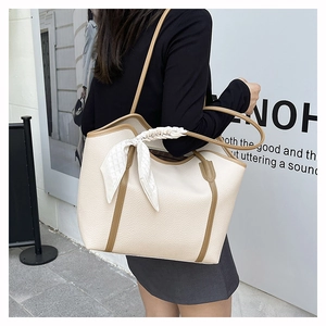Detail of a large cream tote bag with litchi grain faux leather and silk scarf handle