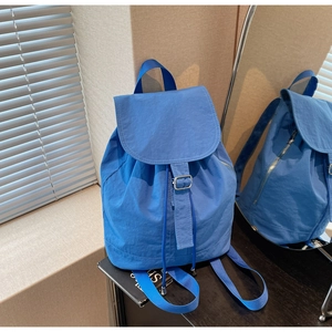 Détail du sac à dos en nylon bleu montrant la fermeture à cordon et la poche latérale zippée