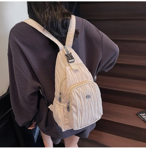 Detail of quilted nylon crossbody bag showing zip pockets and adjustable strap on a model