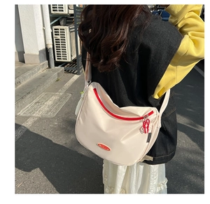 Detail of off-white nylon crescent bag with red contrast zippers and adjustable strap